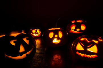 Halloween carved bright orange pumpkin jack lantern with different expressions of immotions on a dark textured background glow brightly in the dark