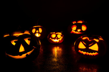 Halloween carved bright orange pumpkin jack lantern with different expressions of immotions on a dark textured background glow brightly in the dark