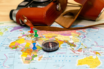 a compass lying on a geographical map marks the place of travel with buttons in the background an old camera is the concept of a tourist