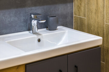 A modern white sink with a metal faucet in the bathroom in a residential building or hotel.