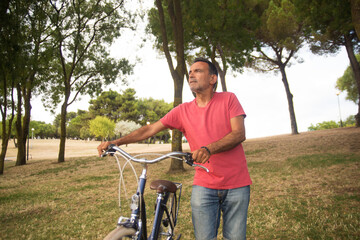 Fototapeta premium Portrait of serious mature man with bicycle. Man riding bike in autumn park. Active seniors concept