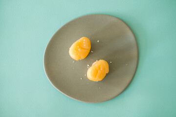 Two Nigiri Sushi with scallop served on light grey plate. Two sushi pieces served on the plate isolated on turquoise background. Japanese food. 