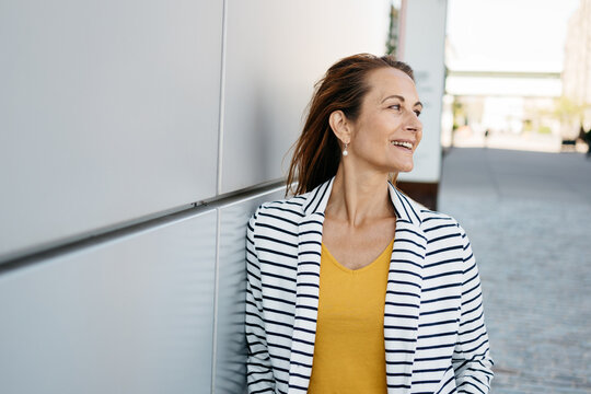 Confident cheerful middle-aged woman looking over her shoulder