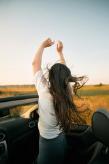 Side view of carefree woman in sunglasses holding hands up