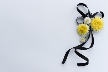 Decoration from black funeral ribbon with yellow flowers.