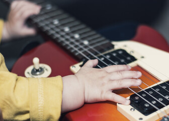 Baby playing the electric guitar. Baby hands on guitar strings. Learning to play the guitar.