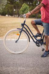 Naklejka premium Side view of man with bicycle in autumn park. Man riding bike along country road. Sport and leisure concept