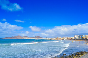 Fototapeta na wymiar Las Palmas beach, white foam waves and high blue sky