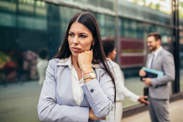 Fototapeta premium Young businesswoman with serious expresison standing at the city.