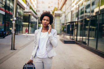 Portrait of excited young business woman using smart phone with travel bag