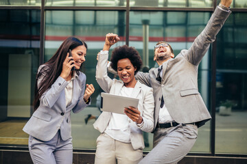 Business team celebrating a triumph, looking at digital tablet.