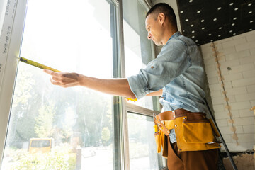 Construction worker installing window in house