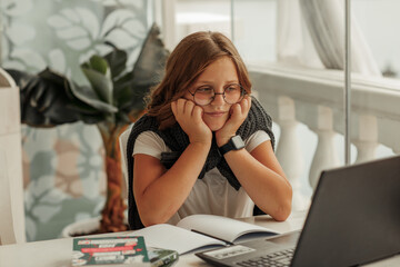 A teenage girl with glasses frowns at a laptop