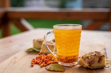 good morning, hot tea with a cake, sea buckthorn berries and blackberry leaves, horizontal