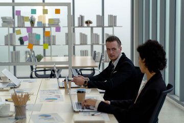 handsome Caucasian businessman talking advice partner and discussing with kindness at meeting table with tablet computer on meeting desk in modern office. boss and employee. working together.