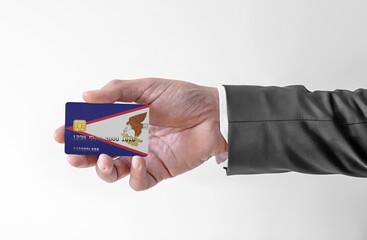 Bank credit plastic card with flag of USA state American Samoa holding man in elegant suit