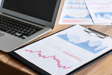 Clipboard with charts on table in office, closeup