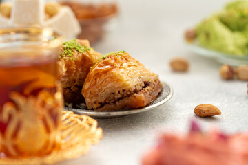Assortment of Turkish delights with glass of tea on gray background
