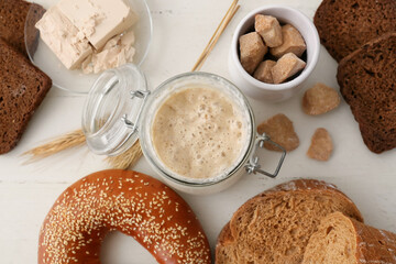 Glass jar with sourdough, bagel and brown sugar on white wooden background