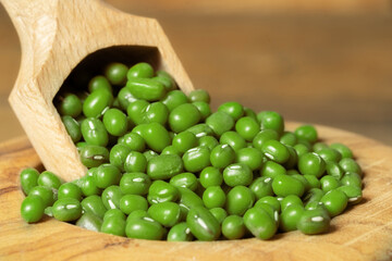 Closeup of soja beans in a bowl with a scoop. Dried green peas in a wooden bowl on wooden background.