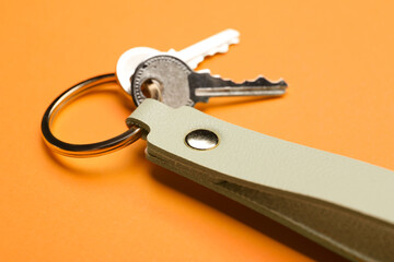 Keys with leather keychain on color background, closeup