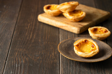 Pasteis de Belem, portuguese egg tart pastries in the brown plate   on wooden table.Copy space