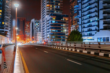 Empty asphalt road with modern buildings at night in Dubai