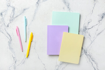 Stylish notebooks and pens on color background