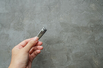 close up people hold stainless nail cutter with left hand for beauty in loft cement background