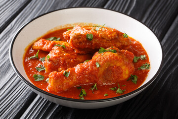 Asian food pieces of chicken stew in tomato sauce with spices close-up in a bowl on the table. horizontal