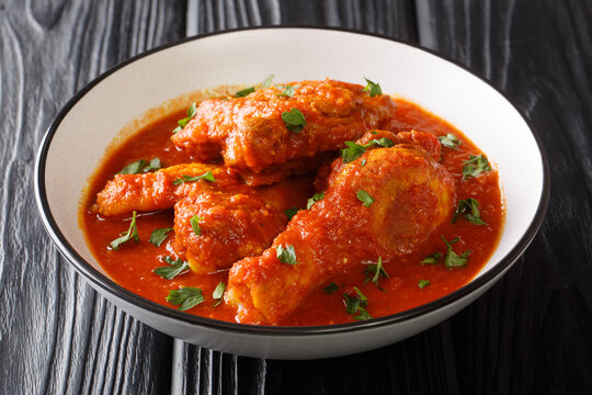 Authentic Ayam Masak Merah Recipe made with chicken pieces that are doused in a spicy tomato sauce close-up in a bowl on the table. Horizontal
