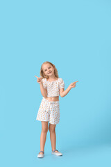 Cute little girl pointing at something on color background