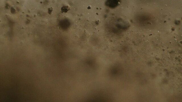 Flying dirt, soil, earth, particles and chunks seen in detail and in slow motion