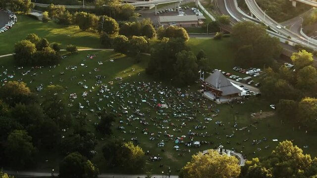 People sitting on grass field in Bushnell park enjoying show, Hartford
