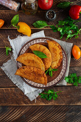 Traditional Crimean Tatar cuisine, chebureki with chicken meat. Fried empanadas on wooden background