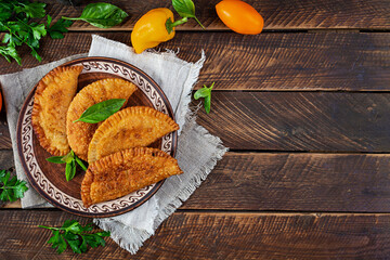 Traditional Crimean Tatar cuisine, chebureki with chicken meat. Fried empanadas on wooden background