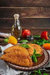 Traditional Crimean Tatar cuisine, chebureki with chicken meat. Fried empanadas on wooden background