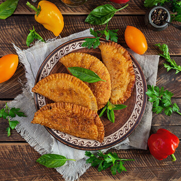 Traditional Crimean Tatar cuisine, chebureki with chicken meat. Fried empanadas on wooden background
