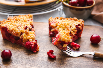 Board with pieces of tasty cherry pie on table, closeup