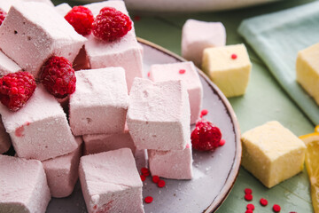 Plate with tasty sweet marshmallows and raspberries on color wooden background