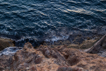 The dark blue sea collides with the rock. Top view