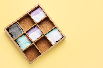 Wooden organizer with different socks on color background