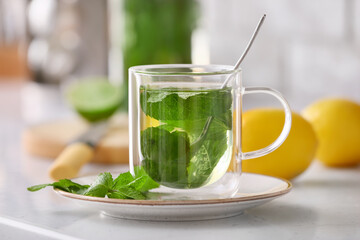 Glass cup of tasty mint tea on table in kitchen, closeup
