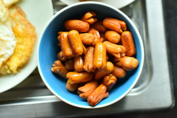 Several crispy fried sausages in a blue cup.
