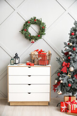Advent calendar with gift boxes in basket, candles on chest of drawers and Christmas wreath on wall in light room