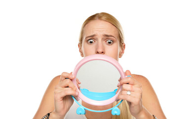 portrait of a young unhappy woman looking her self in the mirror