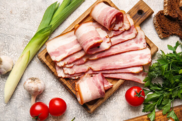 Wooden board with slices of tasty smoked bacon and fresh vegetables on light background