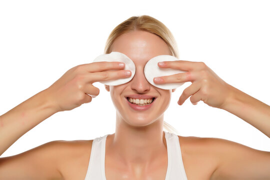 young happy blond woman with headband cleans her face with cotton pads