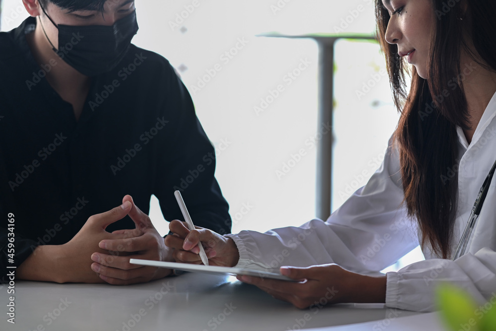 Wall mural female doctor holding digital tablet and explaining medical informations for man patient.