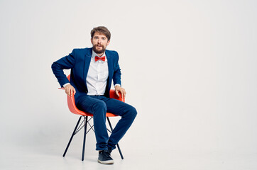 bearded man in suit sitting on red chair posing Professional